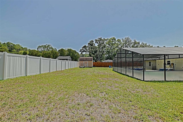 view of yard with a storage shed, an outdoor pool, an outbuilding, and glass enclosure