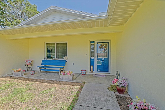 view of exterior entry featuring stucco siding and a porch