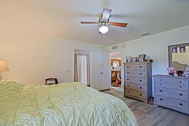 bedroom featuring wood finished floors, a ceiling fan, and a textured ceiling