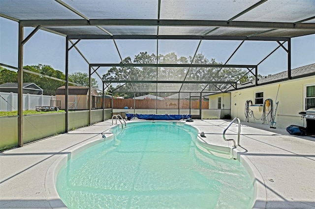 view of swimming pool featuring a patio area, fence, a storage shed, and glass enclosure