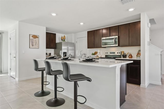 4955 SW 51st Rd, Gainesville, FL 32608 - kitchen featuring stainless steel appliances, light countertops, dark brown cabinetry, a kitchen breakfast bar, and recessed lighting