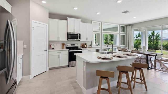 kitchen featuring appliances with stainless steel finishes, a sink, light countertops, backsplash, and white cabinetry