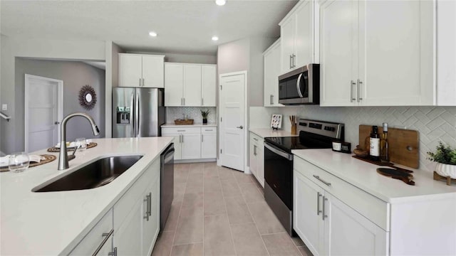 kitchen with stainless steel appliances, a sink, backsplash, light countertops, and recessed lighting