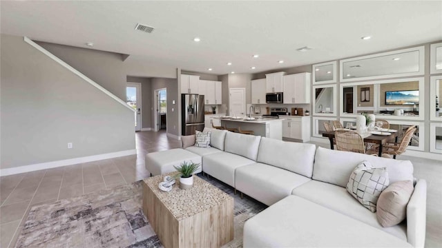 living area with recessed lighting, stairway, baseboards, and light tile patterned floors