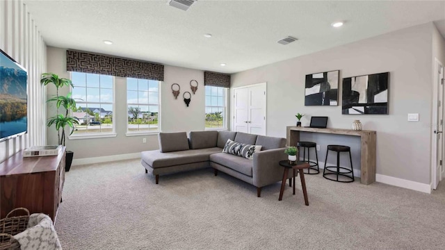 carpeted living area featuring plenty of natural light, baseboards, and recessed lighting