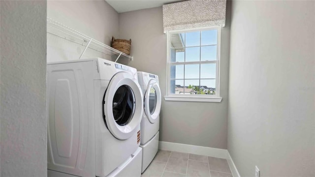 clothes washing area featuring washing machine and clothes dryer, healthy amount of natural light, baseboards, and light tile patterned flooring