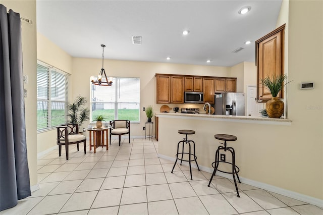 2631 SW 20th Cir, Ocala, FL 34471 - kitchen featuring stainless steel appliances, brown cabinets, a chandelier, baseboards, and a breakfast bar