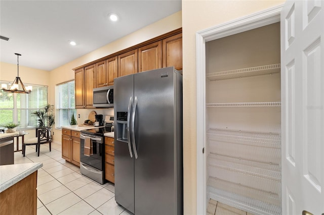 2631 SW 20th Cir, Ocala, FL 34471 - kitchen featuring appliances with stainless steel finishes, light countertops, brown cabinets, light tile patterned floors, and pendant lighting