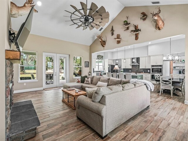 5330 NE 111th Lane Rd, Anthony, FL 32617 - living room featuring a ceiling fan, light wood-type flooring, high vaulted ceiling, a chandelier, and baseboards