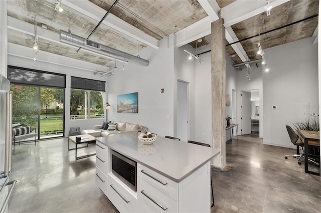 302 SE Broadway St Unit 240, Ocala, FL 34471 - kitchen with stainless steel microwave, a towering ceiling, white cabinetry, concrete flooring, and open floor plan