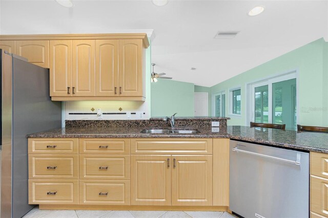 kitchen with appliances with stainless steel finishes, light brown cabinets, a sink, dark stone countertops, and ceiling fan