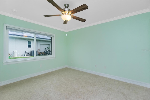 spare room featuring carpet flooring, ceiling fan, crown molding, baseboards, and a smoke detector