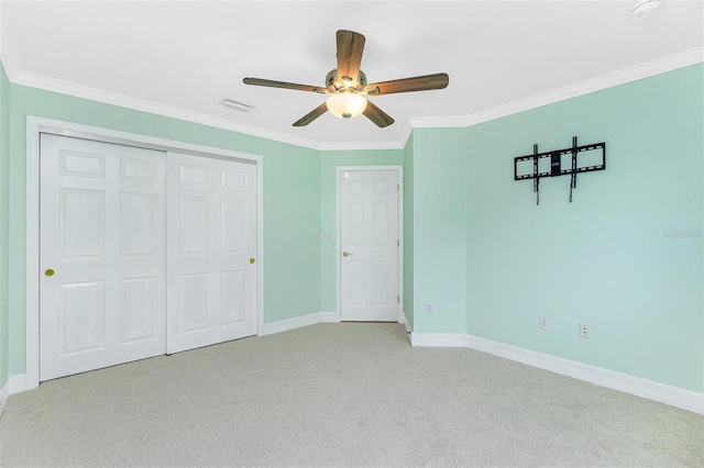 unfurnished bedroom with light colored carpet, ornamental molding, baseboards, a closet, and a ceiling fan