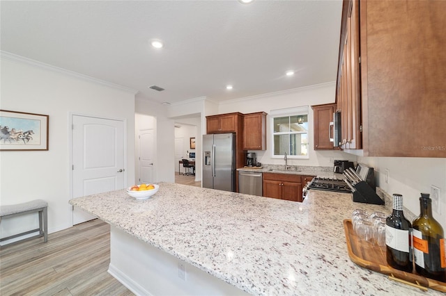9309 SW 106th Ave, Ocala, FL 34481 - kitchen featuring stainless steel appliances, a sink, brown cabinetry, a peninsula, and ornamental molding