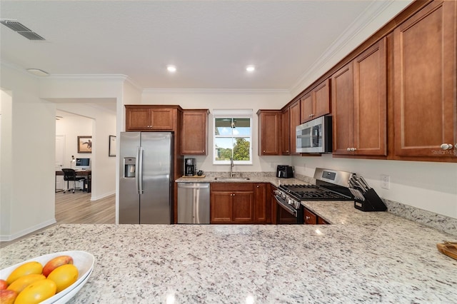9309 SW 106th Ave, Ocala, FL 34481 - kitchen featuring appliances with stainless steel finishes, ornamental molding, a sink, light stone counters, and brown cabinetry