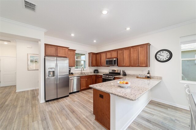 9309 SW 106th Ave, Ocala, FL 34481 - kitchen featuring appliances with stainless steel finishes, a sink, a peninsula, brown cabinetry, and light wood-style flooring
