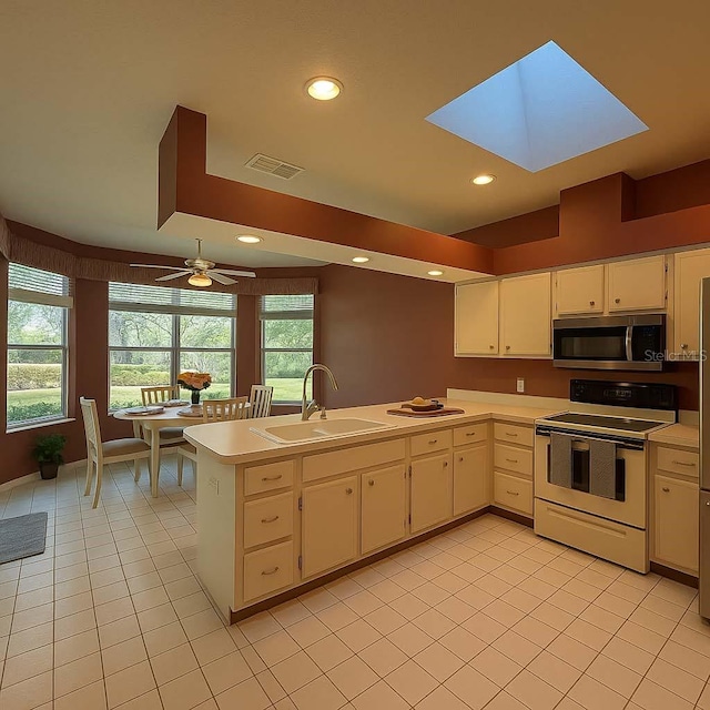 8926 SW 192nd Court Rd, Dunnellon, FL 34432 - kitchen with white range with electric stovetop, stainless steel microwave, a sink, a peninsula, and light countertops