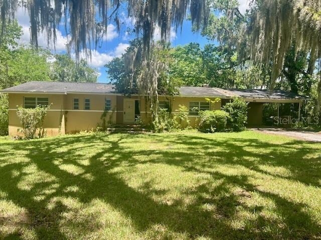 view of front of home featuring a front lawn, an attached carport, and stucco siding
