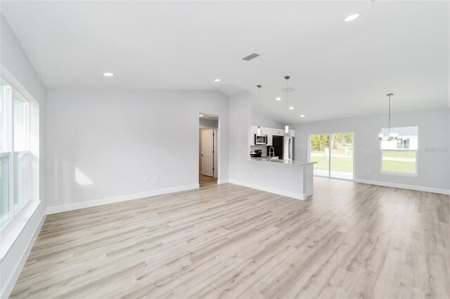 13779 SW 100th Ln, Dunnellon, FL 34432 - unfurnished living room with a chandelier, light wood finished floors, recessed lighting, baseboards, and lofted ceiling