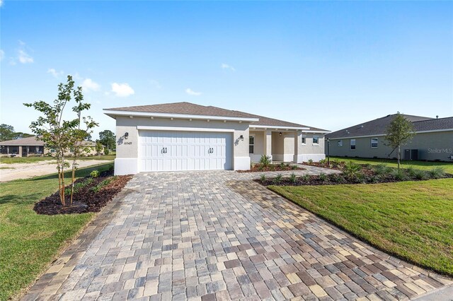 10569 SW 98th Pl, Ocala, FL 34481 - view of front of home featuring a front lawn, decorative driveway, an attached garage, and stucco siding