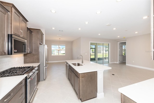 10569 SW 98th Pl, Ocala, FL 34481 - kitchen with stainless steel appliances, a sink, a center island with sink, backsplash, and baseboards
