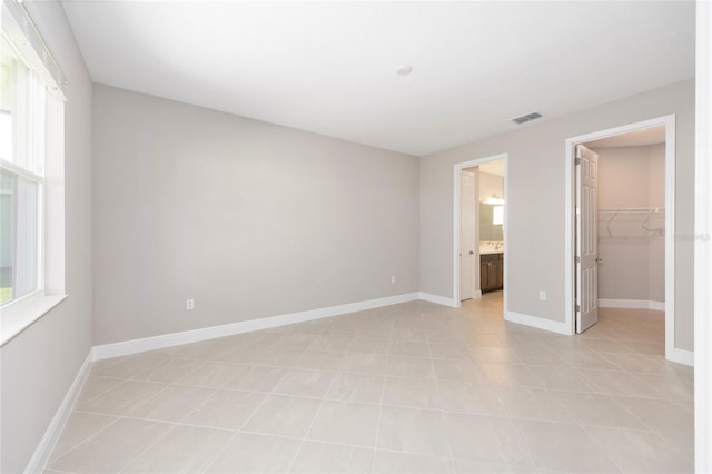 10569 SW 98th Pl, Ocala, FL 34481 - unfurnished bedroom with a walk in closet, baseboards, a closet, light tile patterned floors, and connected bathroom