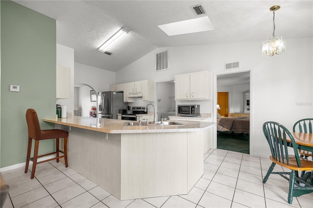 2521 NW 45th Pl, Ocala, FL 34475 - kitchen featuring stainless steel appliances, a sink, a peninsula, vaulted ceiling, and light countertops