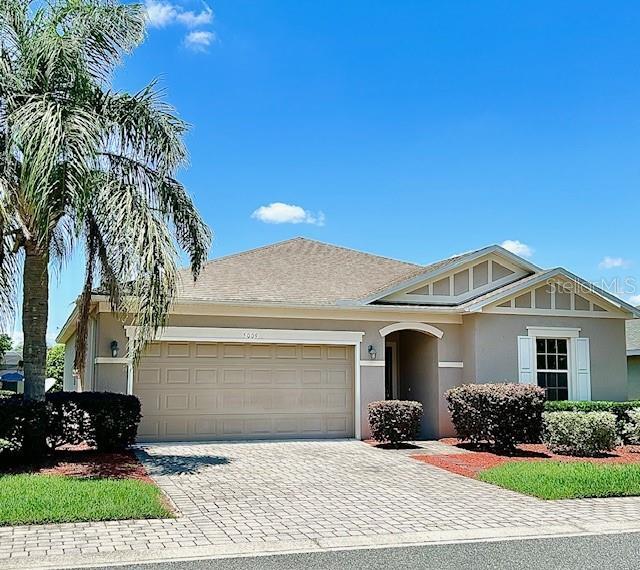 5009 Neptune Cir, Oxford, FL 34484 - view of front facade featuring an attached garage, decorative driveway, and stucco siding