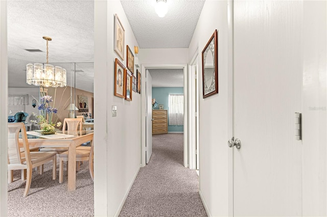 8710 SW 91st St Unit E, Ocala, FL 34481 - hallway featuring carpet flooring, a textured ceiling, a chandelier, and baseboards