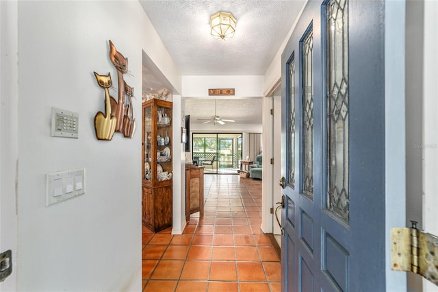 tiled foyer entrance with a textured ceiling and ceiling fan
