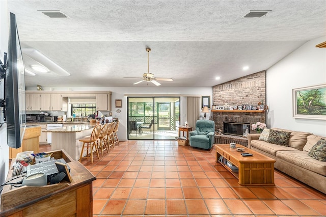 living area with lofted ceiling, a textured ceiling, light tile patterned flooring, ceiling fan, and a brick fireplace