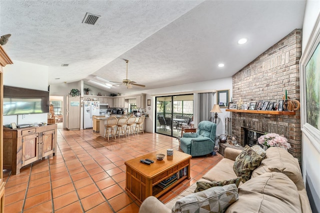 living area with vaulted ceiling, light tile patterned flooring, a fireplace, a ceiling fan, and a textured ceiling