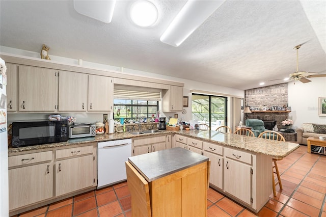 kitchen featuring white dishwasher, black microwave, a peninsula, a sink, and ceiling fan