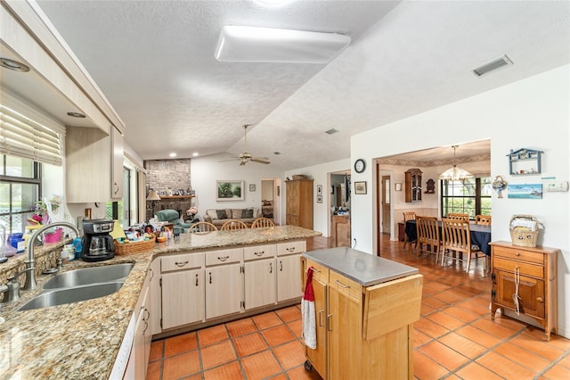 kitchen with a sink, light countertops, a textured ceiling, a peninsula, and light tile patterned flooring