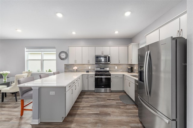 10427 SW 98th Place Rd, Ocala, FL 34481 - kitchen featuring stainless steel appliances, a peninsula, light countertops, decorative backsplash, and dark wood-style flooring