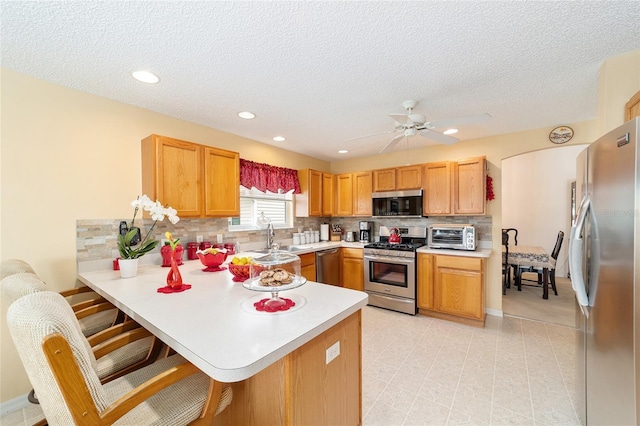 2608 Casso Ct, The Villages, FL 32162 - kitchen featuring stainless steel appliances, a peninsula, light countertops, tasteful backsplash, and a textured ceiling