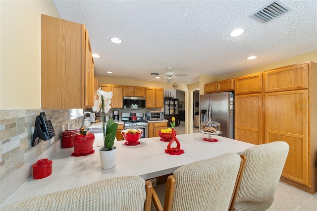2608 Casso Ct, The Villages, FL 32162 - kitchen with stainless steel appliances, a peninsula, arched walkways, ceiling fan, and a breakfast bar area