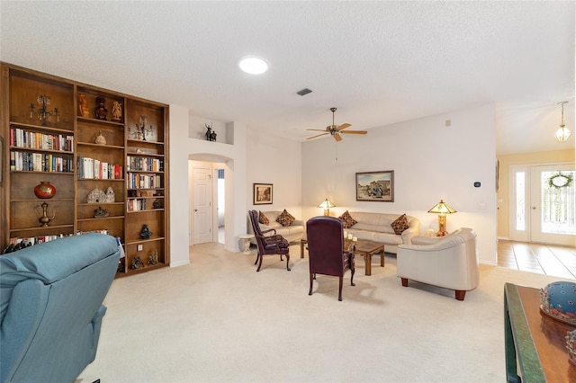 2608 Casso Ct, The Villages, FL 32162 - living room with arched walkways, ceiling fan, light carpet, baseboards, and a textured ceiling