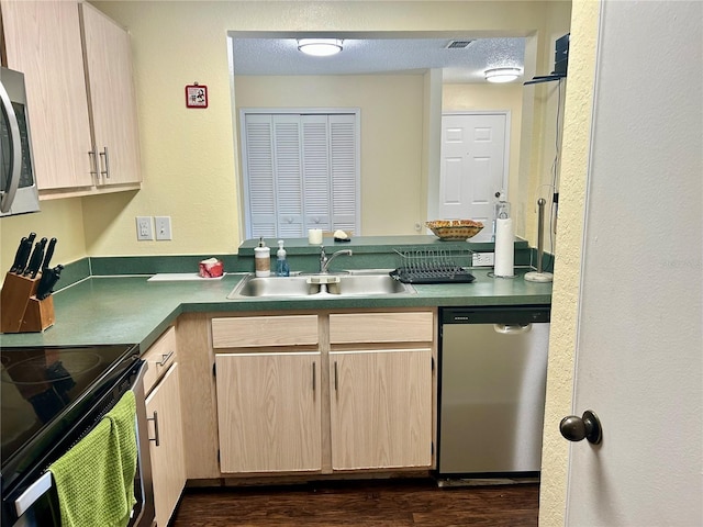 3705 SW 27th St Unit 621, Gainesville, FL 32608 - kitchen with appliances with stainless steel finishes, a sink, light brown cabinetry, dark wood finished floors, and a peninsula