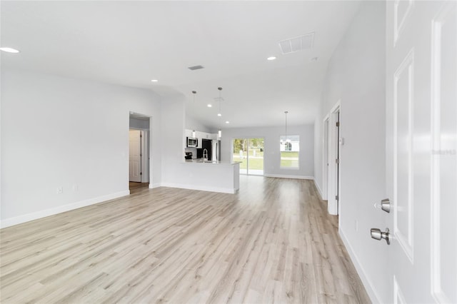 unfurnished living room featuring lofted ceiling, light wood-style floors, baseboards, and recessed lighting