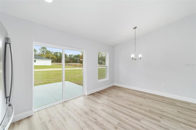 unfurnished dining area featuring a chandelier, light wood finished floors, baseboards, lofted ceiling, and arched walkways