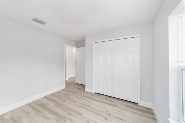 unfurnished bedroom featuring light wood-type flooring, baseboards, and a closet