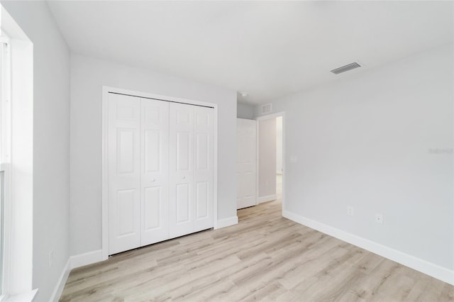 unfurnished bedroom with wood finished floors, baseboards, and a closet
