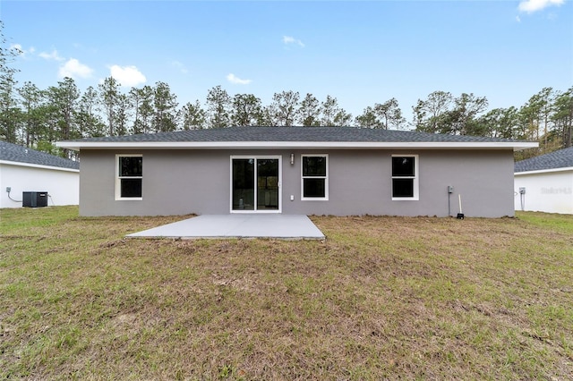 back of property with a patio area, central AC unit, stucco siding, and a lawn