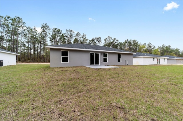 rear view of property with a patio, a lawn, and stucco siding