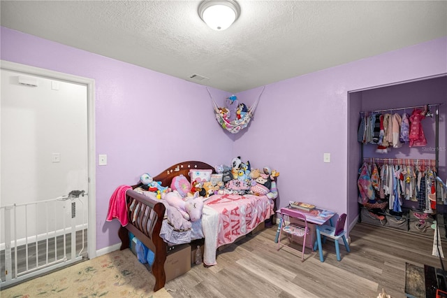 9 Juniper Pass Trl, Ocala, FL 34480 - bedroom with wood finished floors, a textured ceiling, a closet, and baseboards