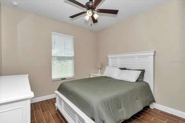 bedroom featuring baseboards, wood finish floors, and ceiling fan