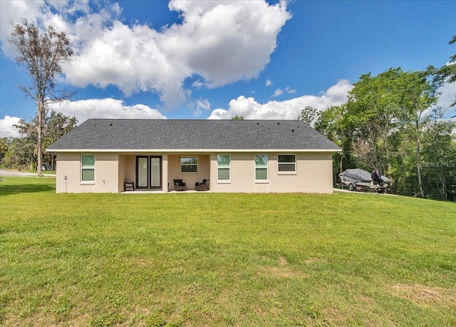 rear view of property with a yard, stucco siding, and a patio area