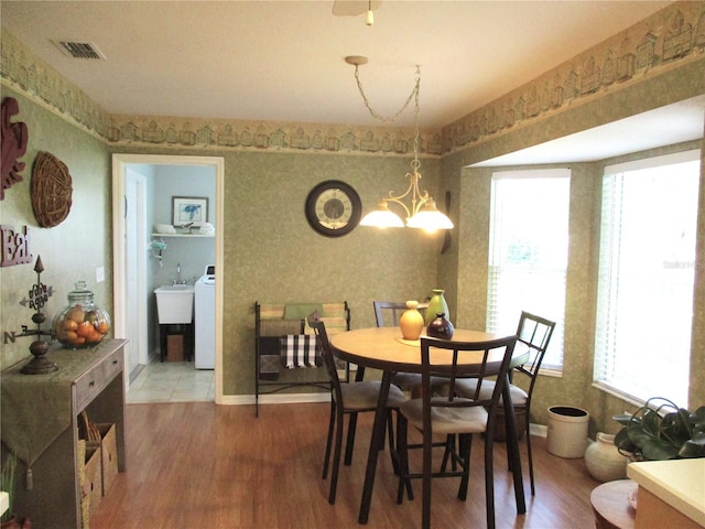 13762 SW 112th Ter, Dunnellon, FL 34432 - dining space with wallpapered walls, wood finished floors, a chandelier, and washer / clothes dryer