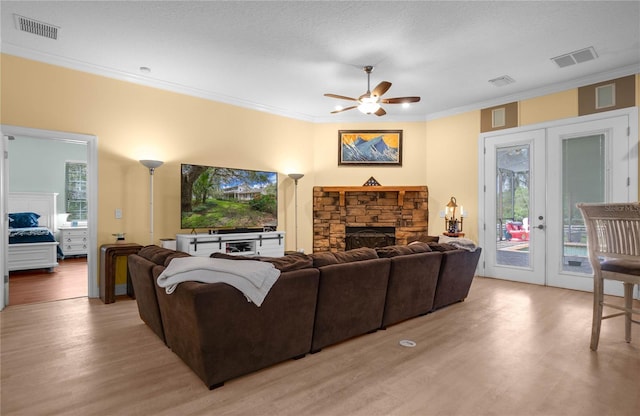 9709 E Baymeadows Dr, Inverness, FL 34450 - living area with ornamental molding, ceiling fan, light wood-type flooring, a stone fireplace, and french doors
